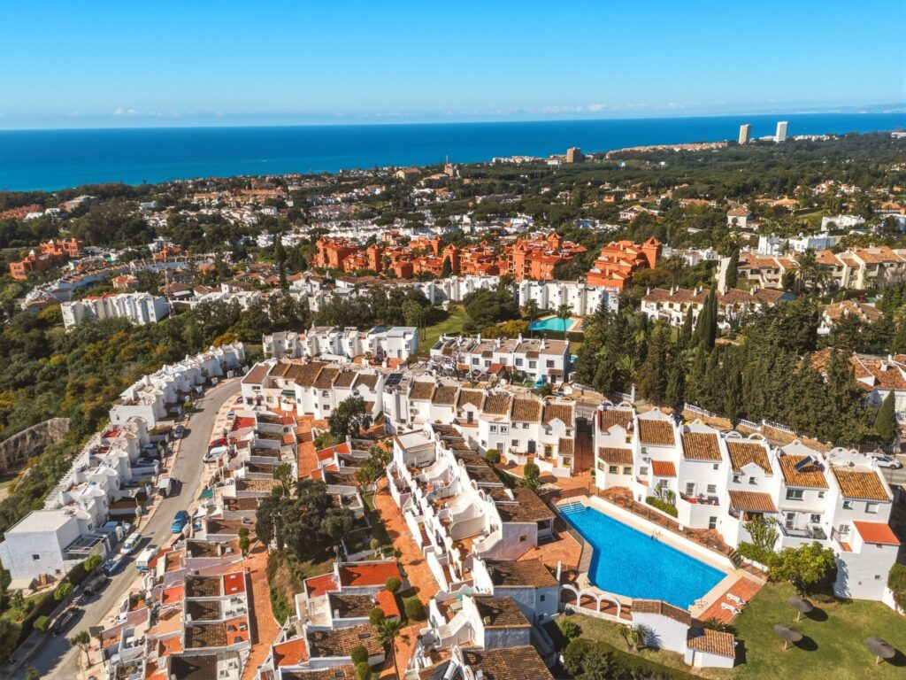 Aerial view of Artola, Cabopino, with the Mediterranean coastline behind the white townhouses of Casa Cabopino Retreat