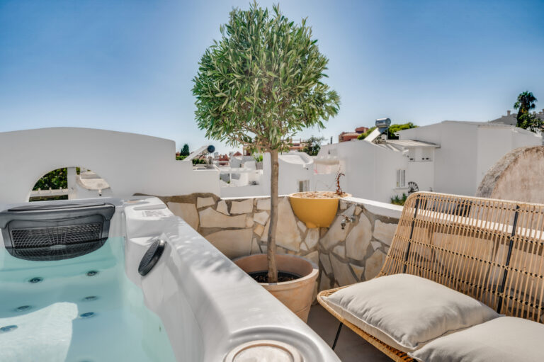 The private roof terrace of Casa Cabopino Retreat with the heated jacuzzi, an olive tree and a lounge seat