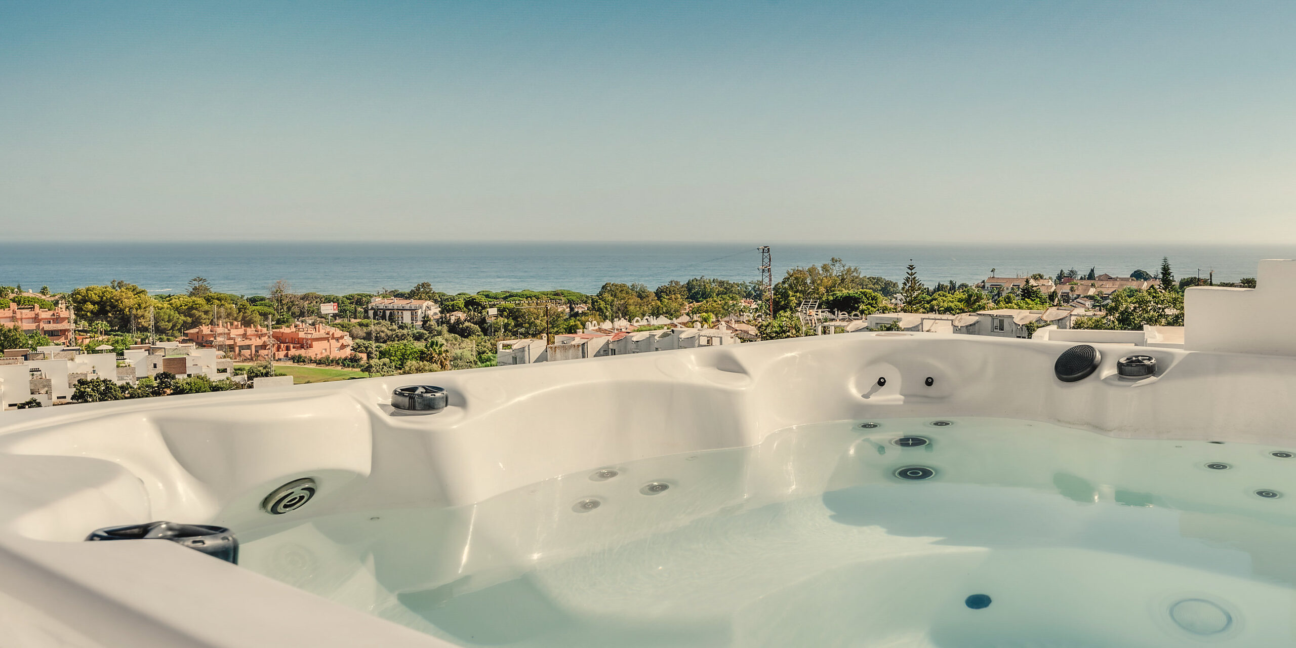 Private heated rooftop jacuzzi at Casa Cabopino Retreat, looking out over Cabopino and the Mediterranean in warm afternoon light