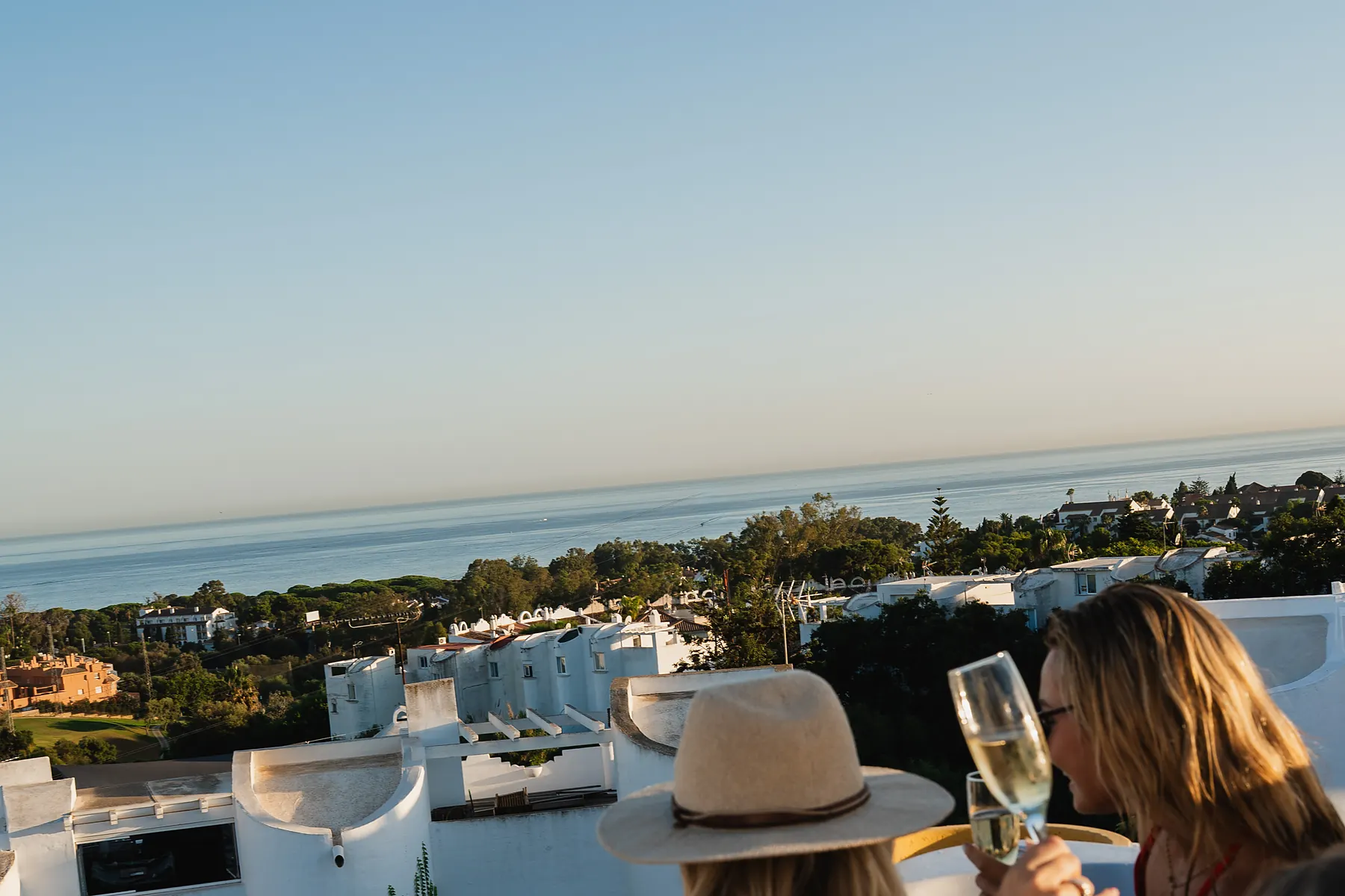 Guests in the heated rooftop jacuzzi at Casa Cabopino Retreat, with white houses and the Mediterranean behind