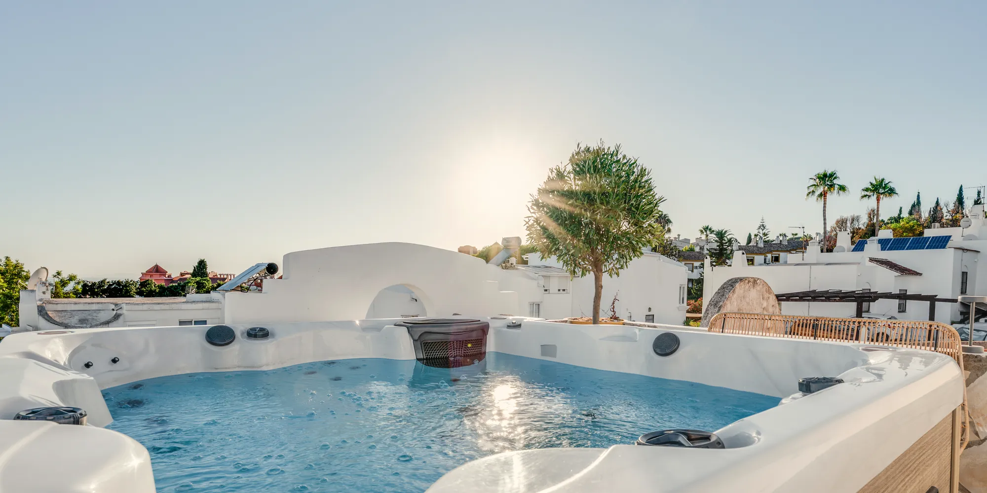 Private heated rooftop jacuzzi at Casa Cabopino Retreat with the low sun over white Andalusian houses and palm trees