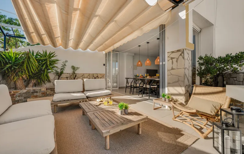 Covered ground-floor terrace with lounge seating under a pergola, opening onto the dining area